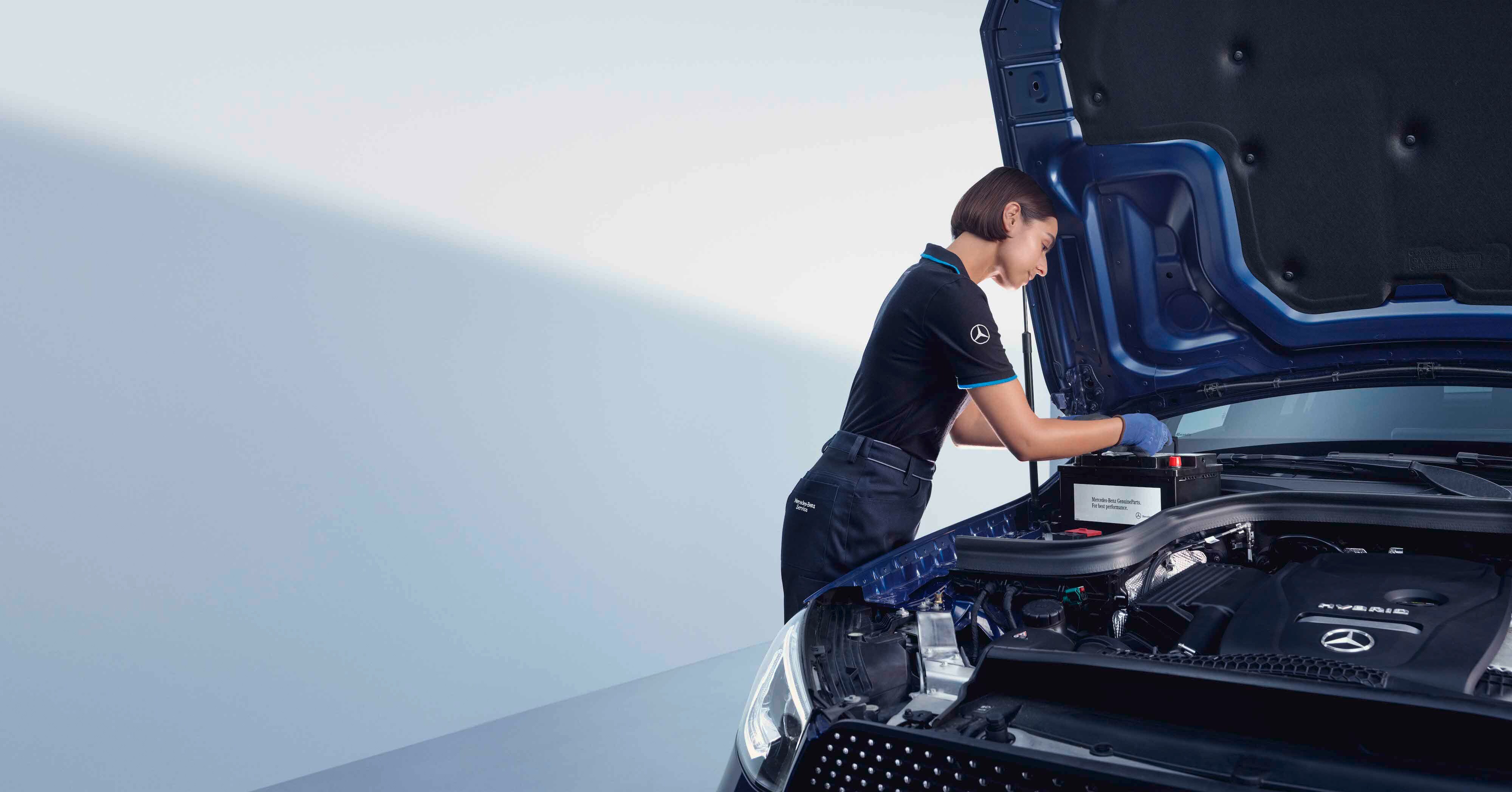Genuine Parts | Mercedes-Benz A automotive mechanic bends over the open bonnet of a Mercedes-Benz.